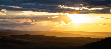 amazing sunset sky over green hills in early summerの写真素材