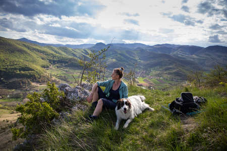 woman trekking in summer landscape with dogの写真素材