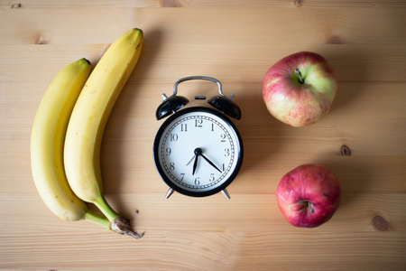 vintage alarm clock and fresh fruit on kitchen table intermittent fastingの写真素材