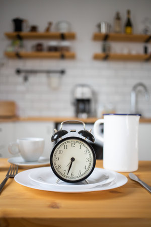 intermittent fasting concept alarm clock on kitchen tableの写真素材