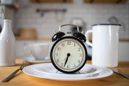 intermittent fasting concept alarm clock on kitchen tableの写真素材