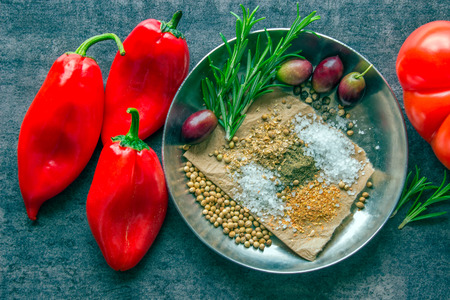 Bright red pepper, spices and olives on a dark table. Ingredients for hot sauce.の写真素材