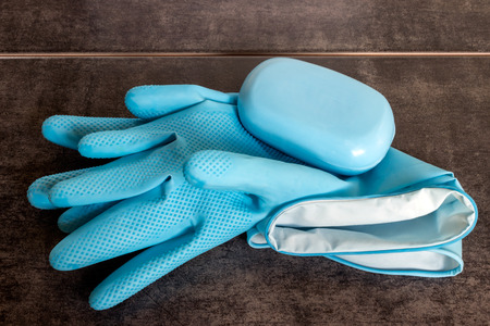 Blue rubber gloves and soap on a dark background. Concept - cleaning, domestic work.  の写真素材