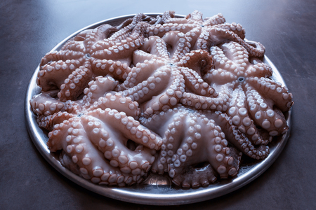 Fresh raw octopus on a large platter. Concept - healthy food, longevity, Mediterranean diet. A big catch.の写真素材