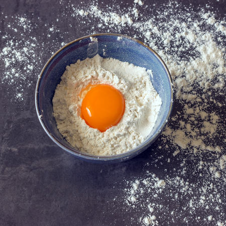 Eggs and flour in the blue bowl. Ingredients for home baking. Delicious Breakfast.の写真素材