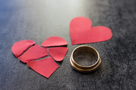 Wedding rings and broken red  heart. Black background. The concept of divorce, parting, infidelity...