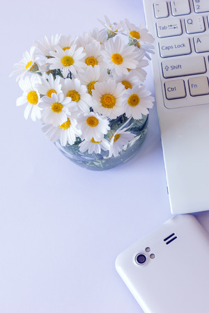 Workspace with computer at home , a desk with flowers and white smartphone. Woman's modern workspace. の写真素材