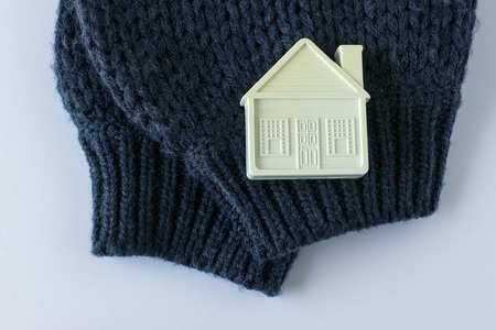  Small white toy house lies on a warm cozy scarf. Concept-insulation of the house, real estate insurance, cozy accommodation.の写真素材