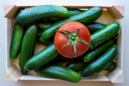 Tomatoes and cucumbers in a wooden crate. Concept- fresh organic vegetables, healthy food from garden. Selective focus.の写真素材