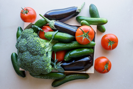 Tomatoes and eggplants, cucumbers and broccoli  in a wooden crate. Concept- fresh organic vegetables, healthy food from garden.の写真素材