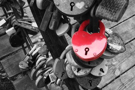 Red heart shaped padlock hangs on the bridge of lovers.  Concept - symbol of love and loyalty.の写真素材