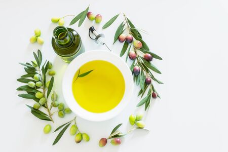 Olive branch and olive oil on light background. Ripe colorful dark and green olives on a branch. Copy space.の写真素材