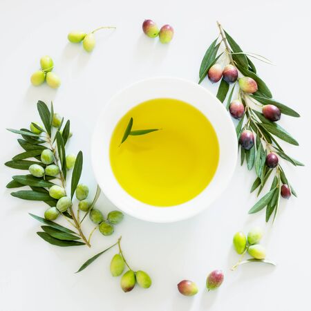 Olive branch and olive oil on light background. Ripe colorful dark and green olives on a branch.の写真素材