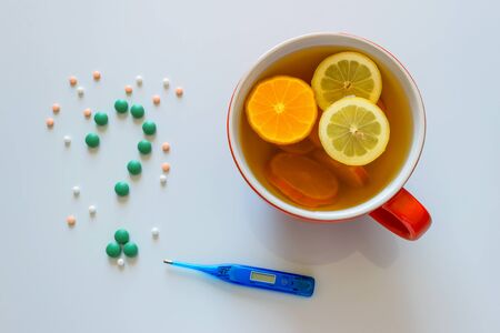 Cup of hot tea with lemon for making a warming drink for flu, coronavirus  and colds. Pills in the form of a question mark.の写真素材