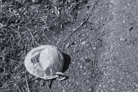 Protective face mask thrown to the ground after use. Consequences of coronavirus pandemic. Contamination concept.の写真素材