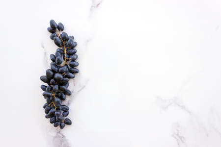 Bunch of ripe dark blue grapes on a white stone table. Concept- healthy diet, vegetarianism, Mediterranean diet.Copy spaceの写真素材