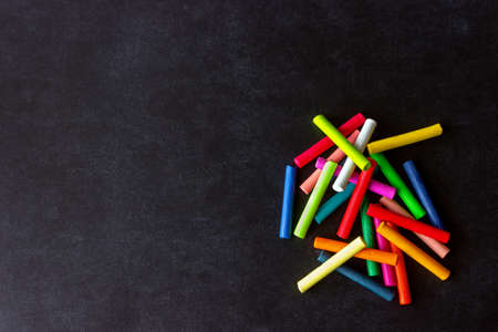 Bright pastel crayons lying on a black school board. Children's creativity. Concept- back to school. Copy space.の写真素材