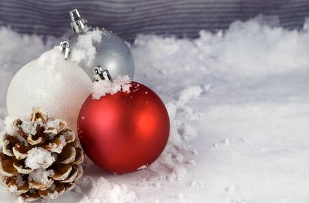 Several festive Christmas ornaments and a pinecone grace this wintery background. Features plenty of space for text.の写真素材