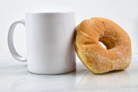 A delicious breakfast featuring a fresh sugar donut and a cup of coffee on a marble tabletop. の写真素材