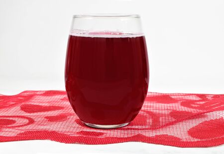 A stemless wineglass with sparkling red wine rests atop an elegant Valentine table runner. Plenty of room to add your own design to the stemless wineglass.の写真素材