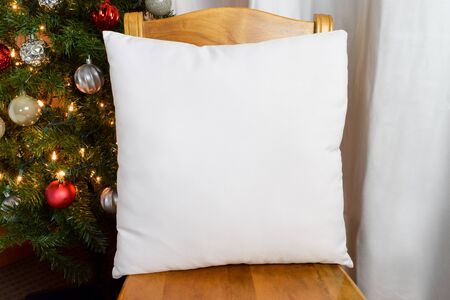 Throw Pillow Mockup Resting on Chair Next to Lit Up Christmas Treeの写真素材