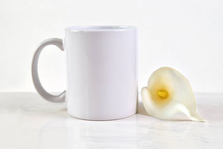 Blank White Mug Mockup featuring an 11 oz. white coffee cup next to a beautiful white Easter Calla Lily.の写真素材
