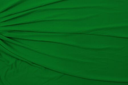 This soft flowing background texture features green fabric draped and taken from a top down view.の写真素材