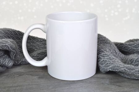Coffee mug mockup chilling on a gray marble background surrounded by a sparkly gray and silver scarf. A snowy white light effect glows in the background.の写真素材