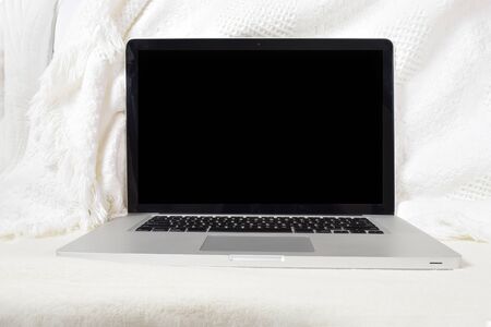 Modern laptop relaxing atop a soft white blanket on the couch. Has clipping path inside the screen to make adding your own image to the screen easier.の写真素材
