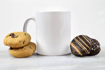 Coffee mug resting on a gray marble  surrounded by chocolate chip and chocolate cookies.の写真素材