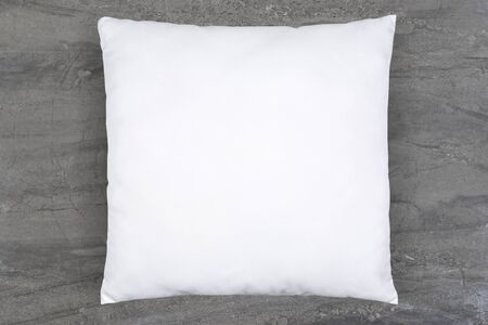A white throw pillow elegantly reclines atop a luxurious gray marble background. Plenty of copy space to add your own design to this throw pillow mockup.の写真素材