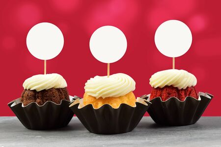 This Valentine cupcake mockup features three delicious gourmet cupcakes on a gray marble background. Glowing red lights add a touch of romance to this cupcake topper mock up.の写真素材