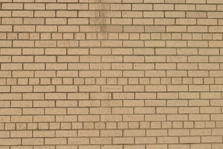 Grunge tan brick wall taken outdoors on a sunny dayの写真素材