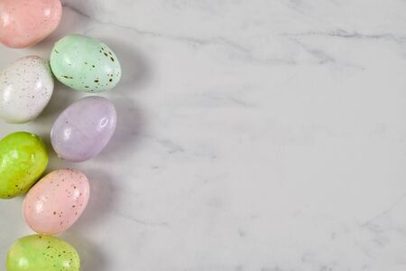 Colorful speckled Easter eggs resting joyously on a white marble background.の写真素材