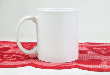 11 ounce white coffee cup resting romantically on a detailed red Valentineâs Day table runner.の写真素材