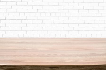 Photo of a light brown wooden table next to a white brick wall.の写真素材