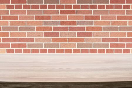 Wood table next to a rustic red brick wall.の写真素材