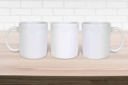 Three 11 ounce coffee mugs chilling on a light wood table.の写真素材