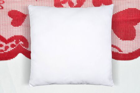 Square white throw pillow resting romantically on a Valentineâs table runner with hearts.の写真素材