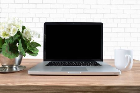 Laptop rests happily on a light wooden table surrounded by hydrangeas and a coffee cup.の写真素材