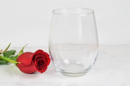 A no stem wineglass chills romantically next to a long stemmed red rose.の写真素材