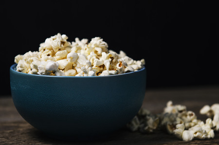 Popcorn in a blue bowl on wooden tableの写真素材