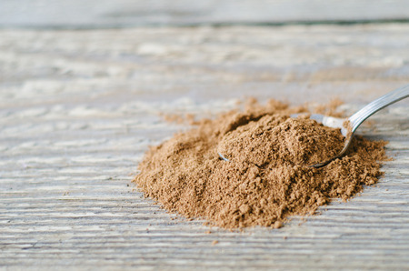 ground cinnamon sprinkled on a spoon and a wooden tableの写真素材