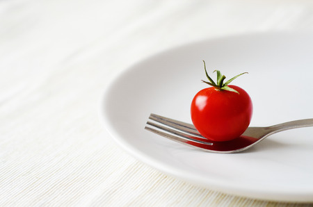 tomato served on white ceramic plate with forkの写真素材