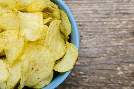 chips with herbs in blue bowl on a wooden table