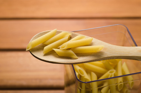 pasta in a transparent container with a wooden spoon