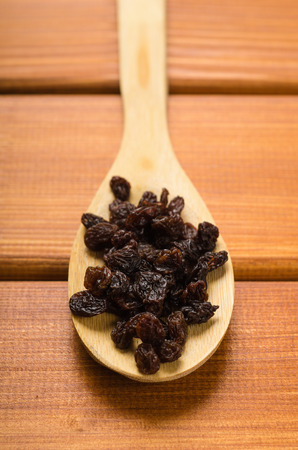 wooden spoon with black raisins on a wooden tableの写真素材