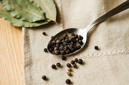 Black pepper peas bay leaf a spoon napkin wooden tableの写真素材