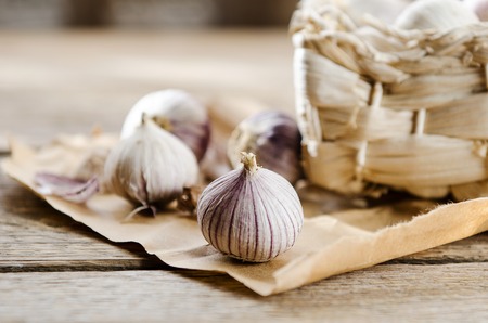 Basket with small heads of garlic on wooden background on kraft paperの写真素材
