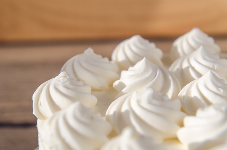 White cream on cake in the sun Background, texture Wooden tableの写真素材